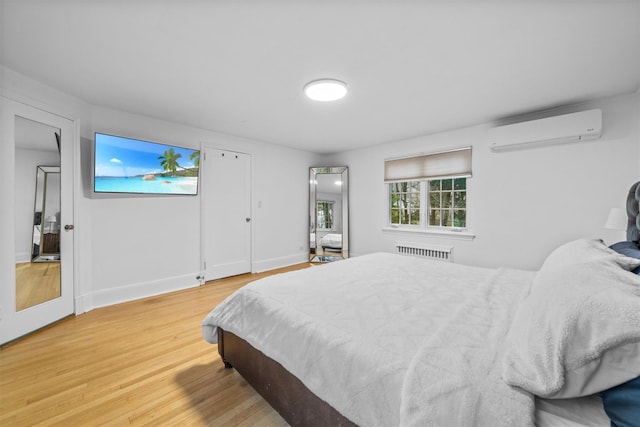 bedroom featuring a wall mounted air conditioner, hardwood / wood-style floors, and radiator