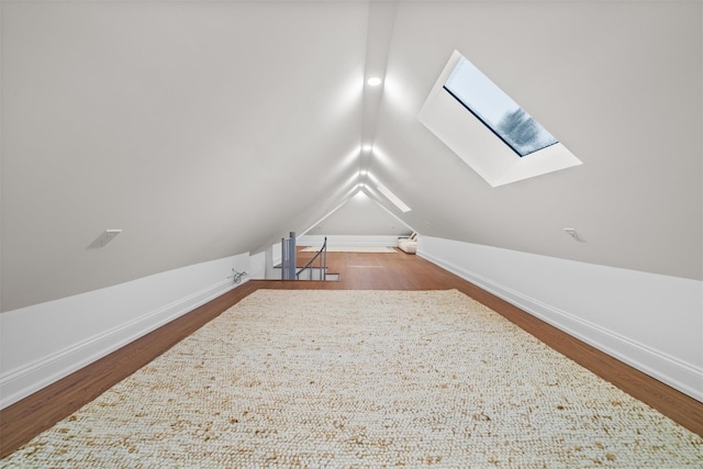 additional living space featuring hardwood / wood-style flooring and lofted ceiling with skylight