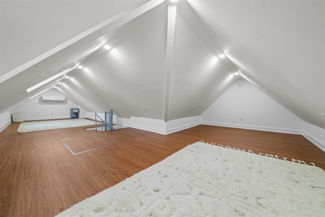 additional living space with wood-type flooring, a wall mounted AC, and lofted ceiling