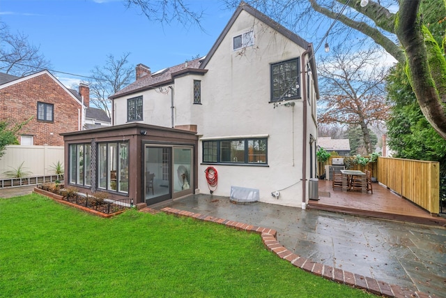 rear view of property with a sunroom, a yard, and a wooden deck