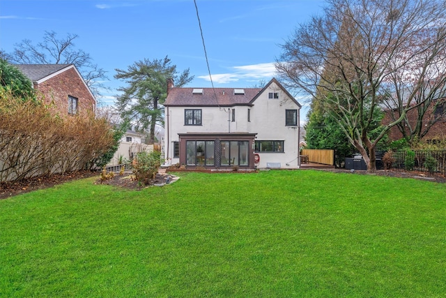 rear view of property featuring a sunroom and a lawn