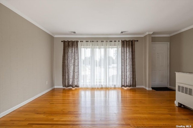 unfurnished room featuring crown molding, light hardwood / wood-style floors, and radiator heating unit