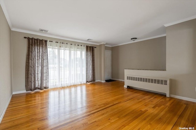 empty room with radiator, crown molding, and light wood-type flooring