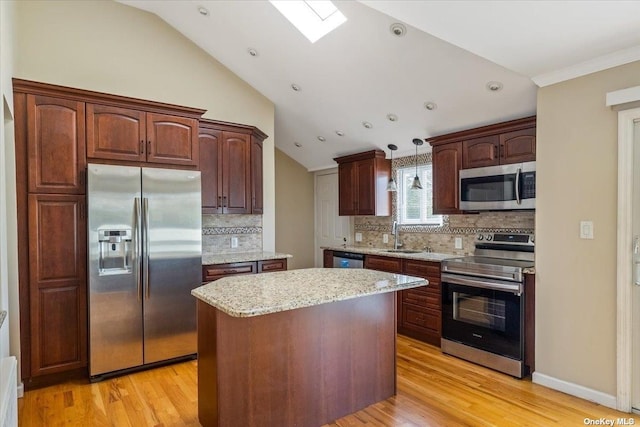 kitchen with lofted ceiling with skylight, a kitchen island, pendant lighting, decorative backsplash, and appliances with stainless steel finishes