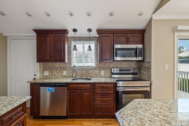 kitchen featuring light stone countertops, appliances with stainless steel finishes, sink, backsplash, and crown molding