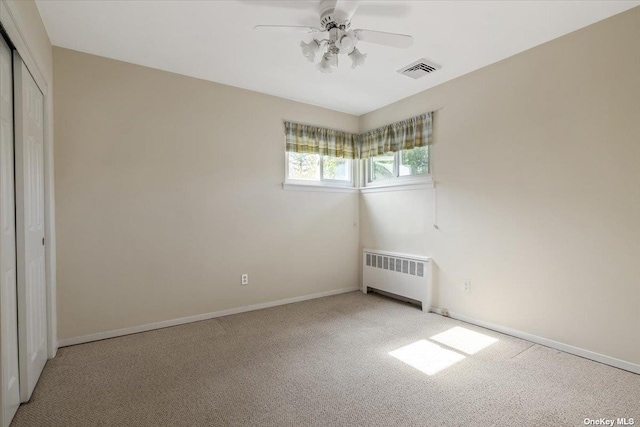 unfurnished bedroom with ceiling fan, light carpet, radiator, and a closet