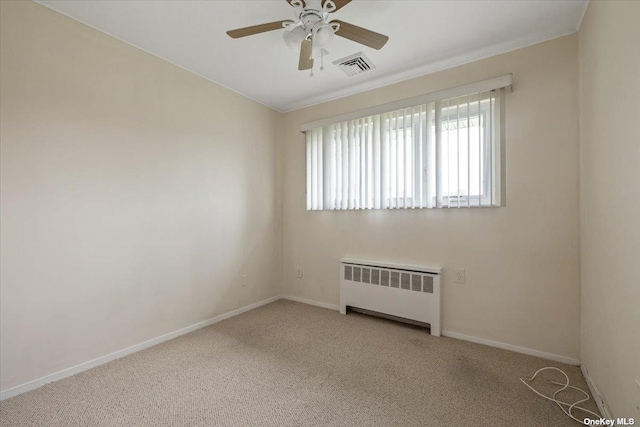 empty room featuring light carpet, ceiling fan, and radiator heating unit