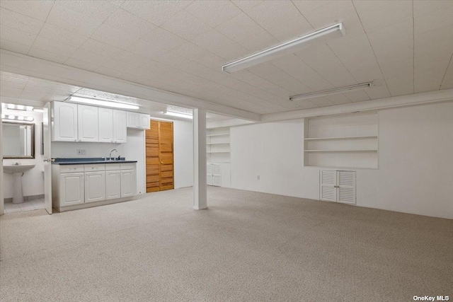 basement featuring sink and light colored carpet