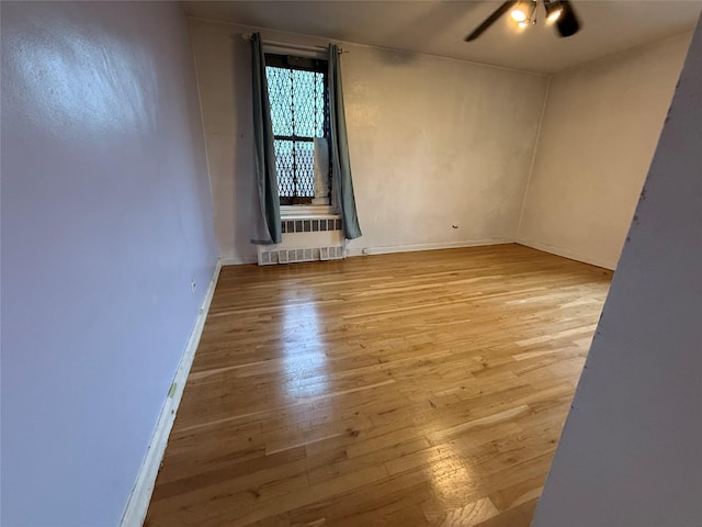 unfurnished room with radiator heating unit, light hardwood / wood-style flooring, and ceiling fan