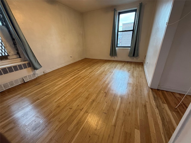 unfurnished room featuring radiator heating unit and light hardwood / wood-style flooring