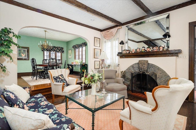 living room with wood-type flooring, a textured ceiling, an inviting chandelier, and beam ceiling