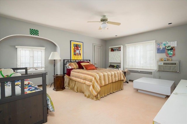 bedroom featuring a wall mounted air conditioner, radiator heating unit, carpet floors, and ceiling fan