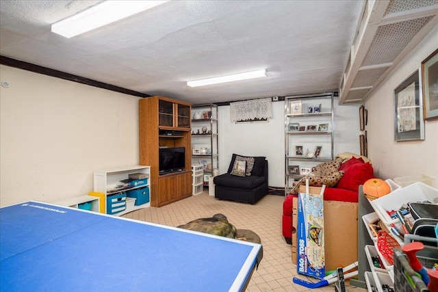 recreation room featuring a textured ceiling and ornamental molding