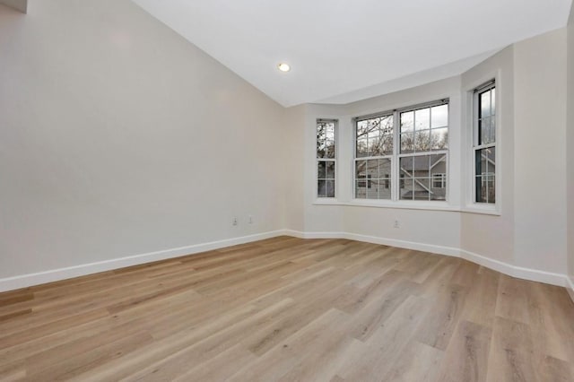 empty room featuring light hardwood / wood-style floors and vaulted ceiling