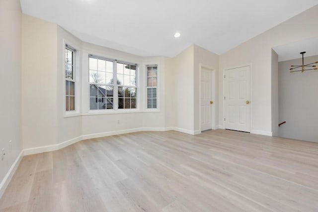 unfurnished room featuring light hardwood / wood-style floors and an inviting chandelier