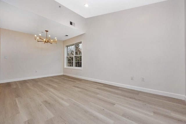 empty room with light hardwood / wood-style flooring and a chandelier