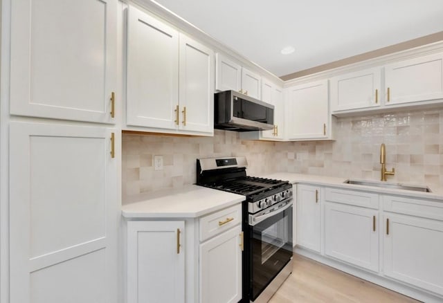 kitchen featuring decorative backsplash, stainless steel appliances, sink, light hardwood / wood-style flooring, and white cabinets