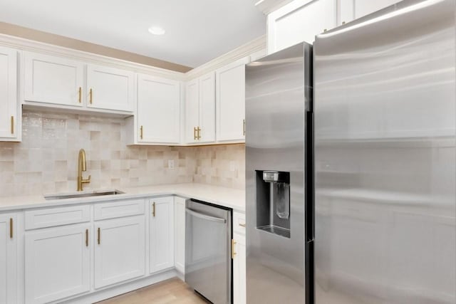 kitchen with appliances with stainless steel finishes, tasteful backsplash, sink, light hardwood / wood-style floors, and white cabinetry