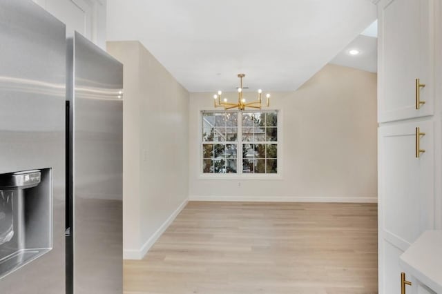 dining room with light wood-type flooring and an inviting chandelier