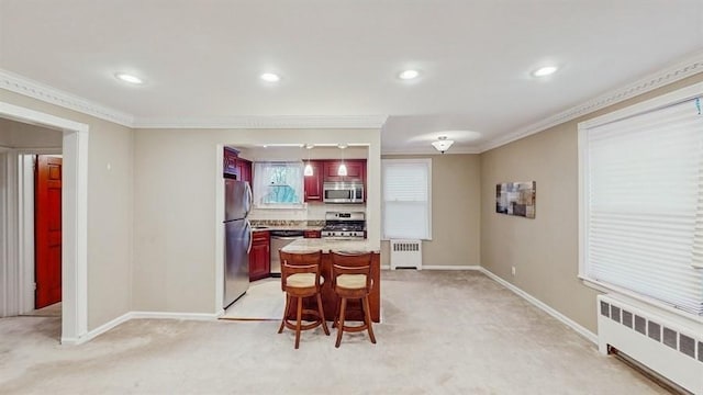 kitchen with light carpet, radiator heating unit, ornamental molding, and appliances with stainless steel finishes