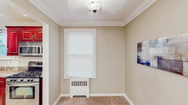 kitchen with ornamental molding, stainless steel appliances, radiator, and light carpet