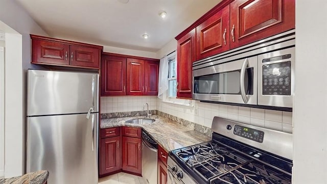 kitchen featuring backsplash, stainless steel appliances, light stone counters, and sink