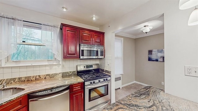 kitchen with crown molding, light stone counters, backsplash, and appliances with stainless steel finishes