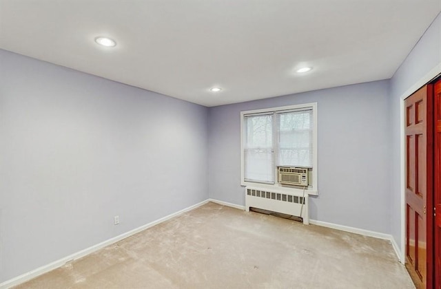 spare room with radiator heating unit, cooling unit, and light colored carpet