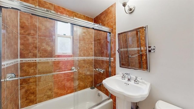 full bathroom with sink, toilet, and bath / shower combo with glass door