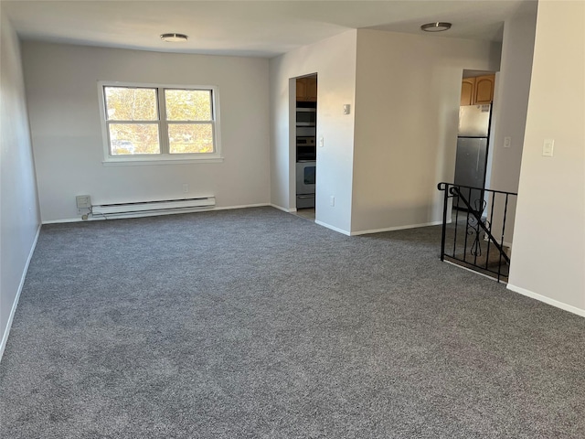 carpeted spare room with a baseboard heating unit