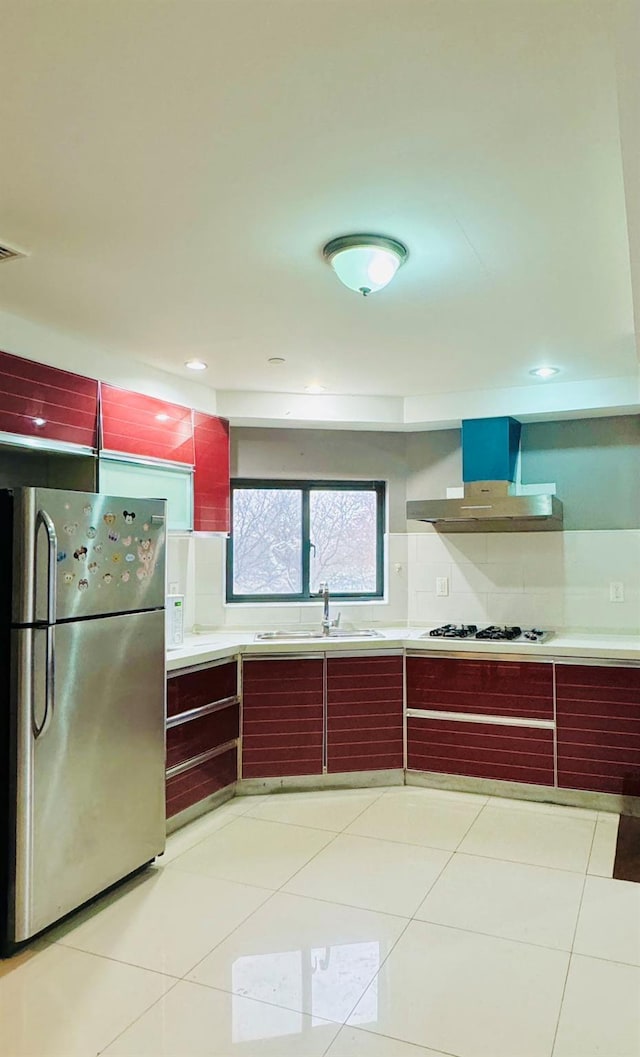 kitchen featuring stainless steel fridge, white gas stovetop, sink, exhaust hood, and light tile patterned flooring