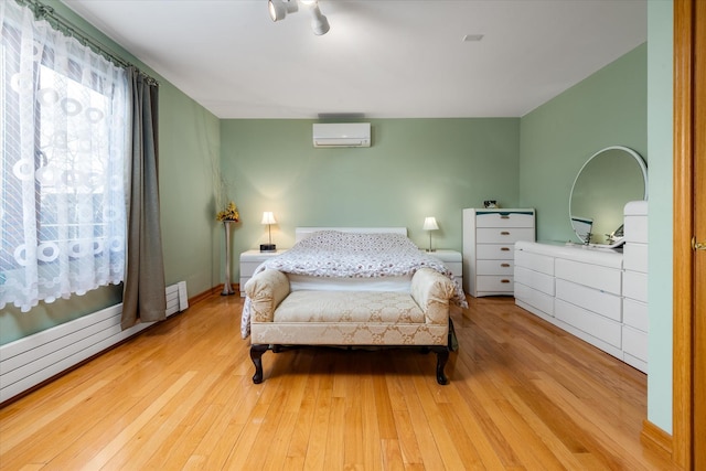 bedroom with light hardwood / wood-style floors and a wall unit AC