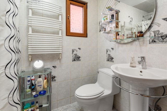 bathroom featuring tile patterned flooring, toilet, radiator heating unit, and tile walls