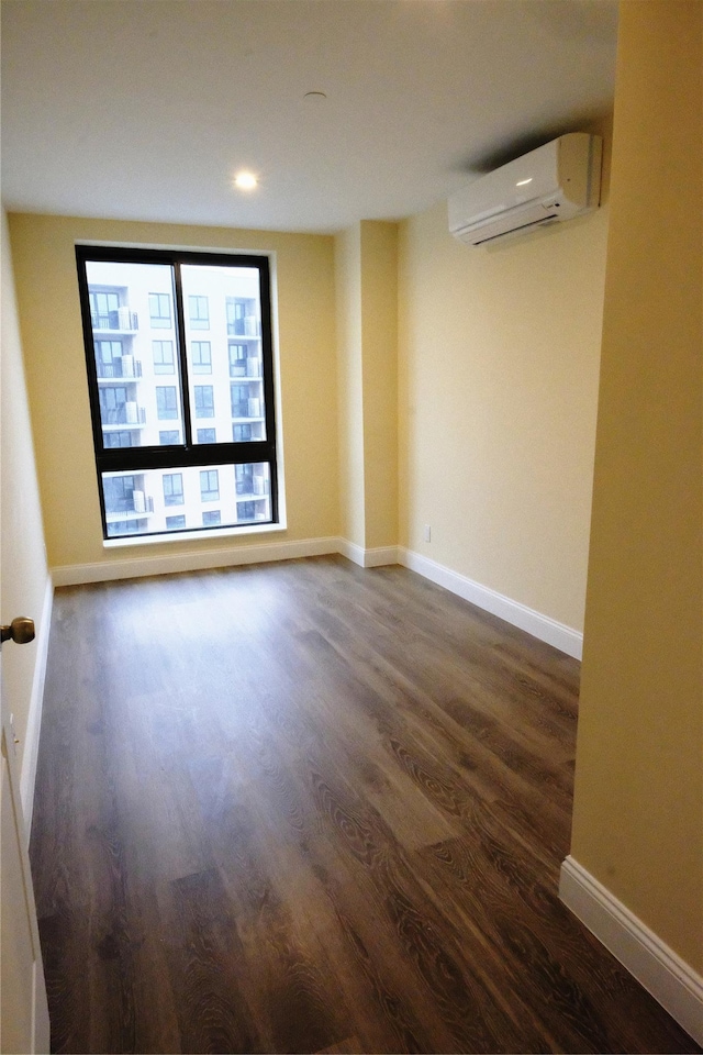 unfurnished room featuring dark hardwood / wood-style flooring and an AC wall unit