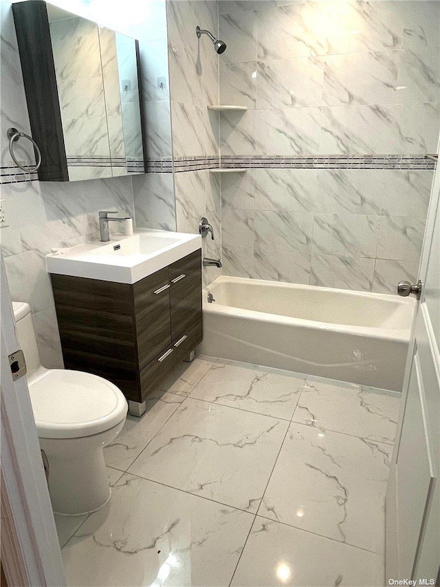 full bathroom with vanity, toilet, tiled shower / bath, and tile walls