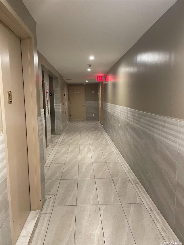 hallway with tile walls and light tile patterned flooring