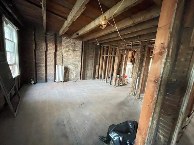 misc room featuring plenty of natural light, brick wall, and radiator heating unit