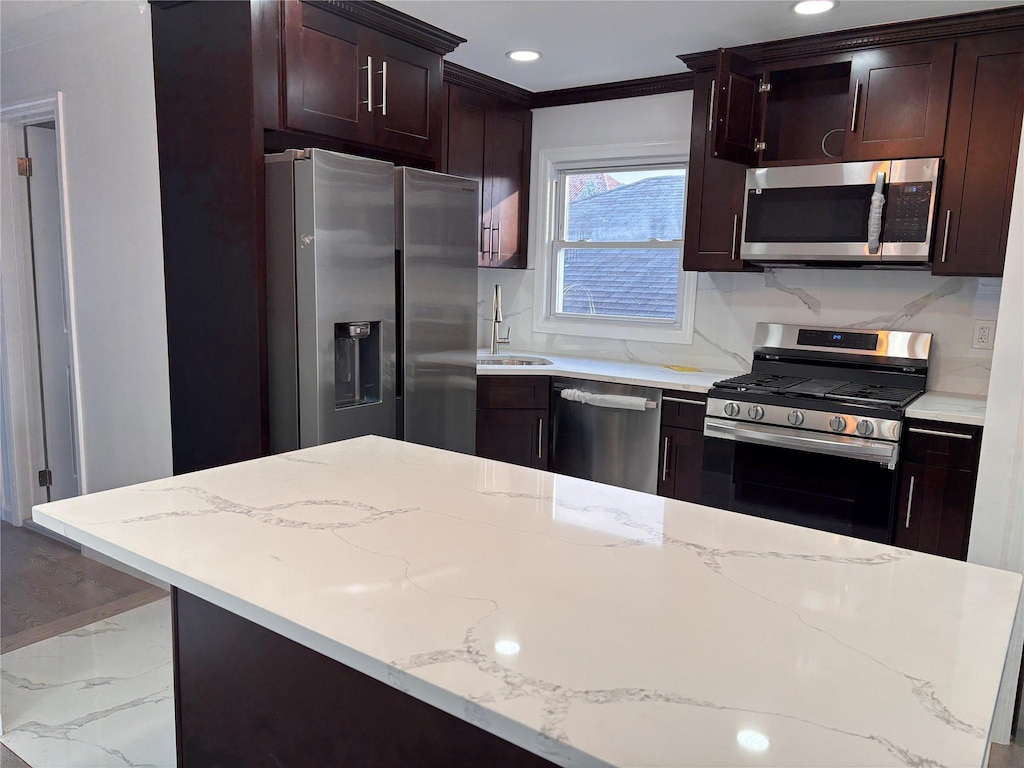 kitchen featuring light stone countertops, stainless steel appliances, and ornamental molding