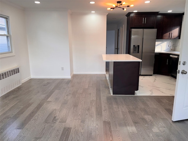 kitchen with stainless steel refrigerator with ice dispenser, sink, radiator heating unit, a center island, and light hardwood / wood-style floors