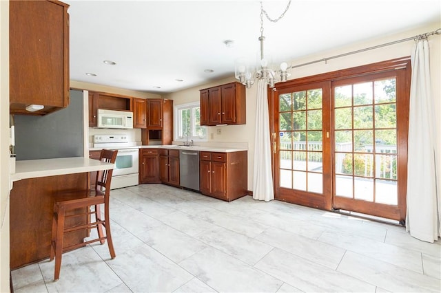 kitchen featuring white appliances, decorative light fixtures, a kitchen bar, kitchen peninsula, and a chandelier