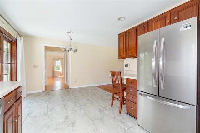 kitchen featuring pendant lighting, stainless steel appliances, an inviting chandelier, and a healthy amount of sunlight