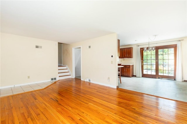 unfurnished living room featuring light hardwood / wood-style floors and a notable chandelier