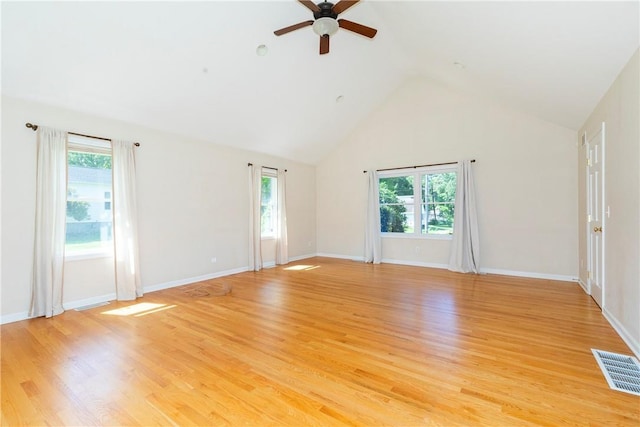 empty room featuring ceiling fan, a healthy amount of sunlight, high vaulted ceiling, and light hardwood / wood-style flooring