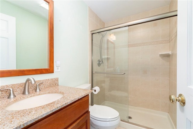 bathroom featuring vanity, toilet, and a shower with door