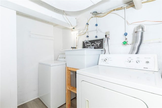 clothes washing area with light hardwood / wood-style flooring and washer and dryer