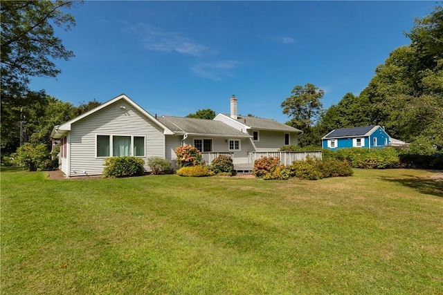 back of property featuring a lawn and a wooden deck