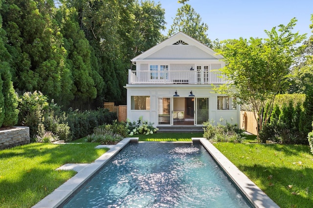 back of house featuring a lawn and a balcony