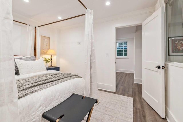 bedroom with ornamental molding and dark wood-type flooring