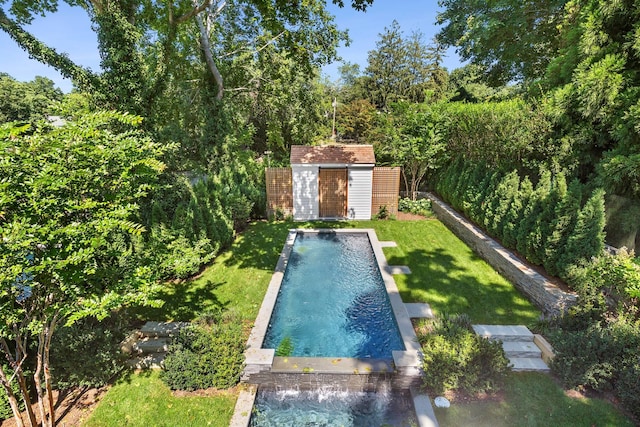 view of swimming pool with a lawn, pool water feature, and a storage shed