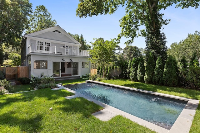 back of house with a yard, a balcony, and a fenced in pool